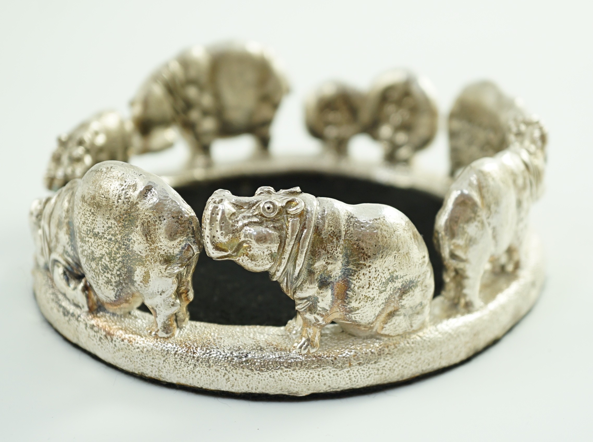 Patrick Mavros - A modern novelty silver bottle coaster, modelled as a continuous bloat of hippopotami, in various positions